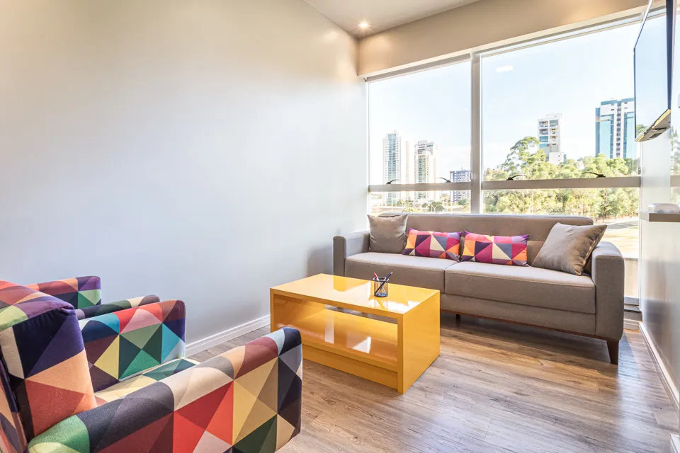 Sala Design da Blocks com poltronas coloridas e vista para a cidade